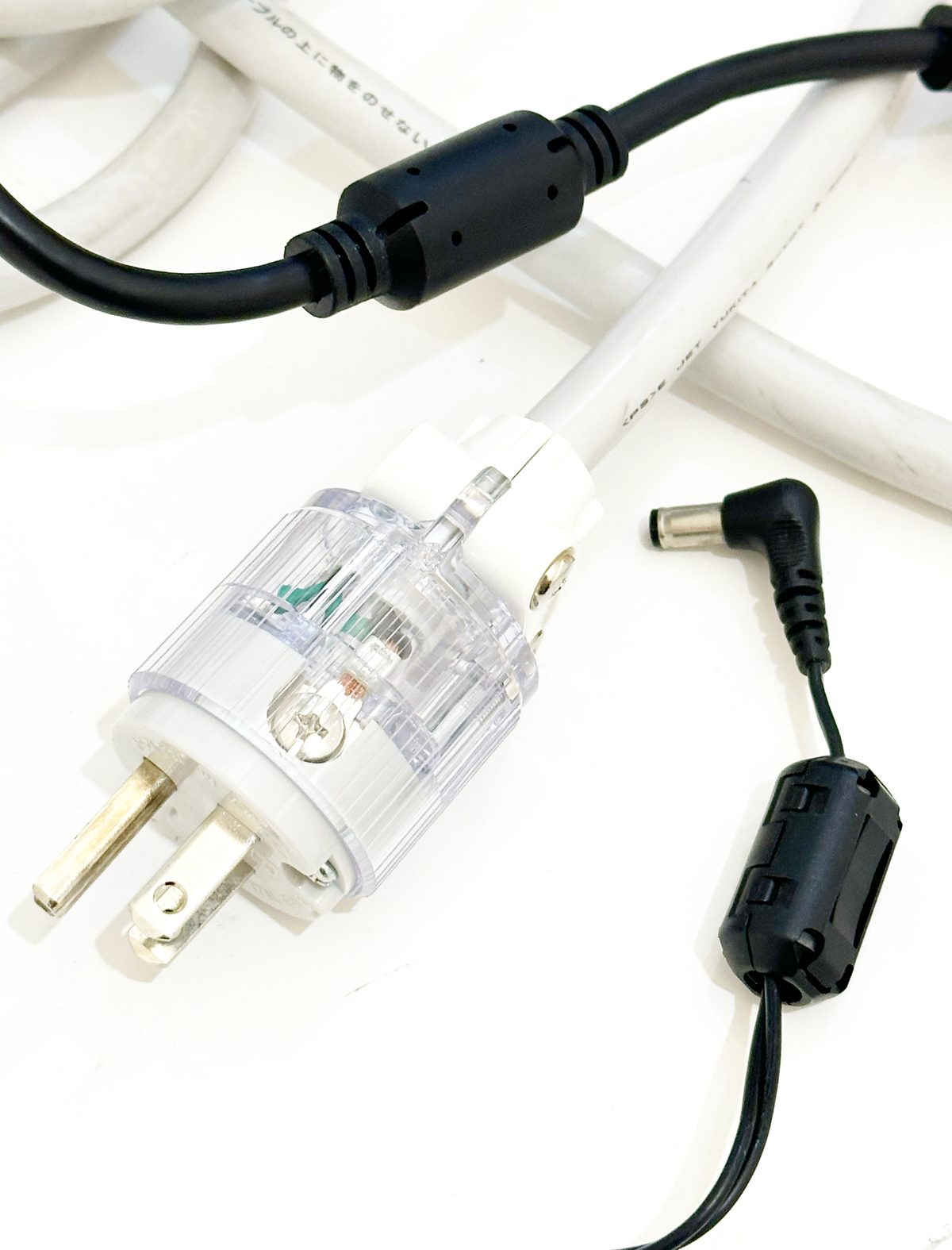 医療用の電源プラグと、ケーブルに通したフェライトコアの写真